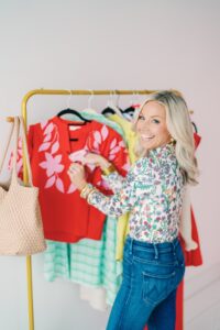 Fashion and lifestyle creator Bobbi Thomas poses with a rack of her outfit picks.